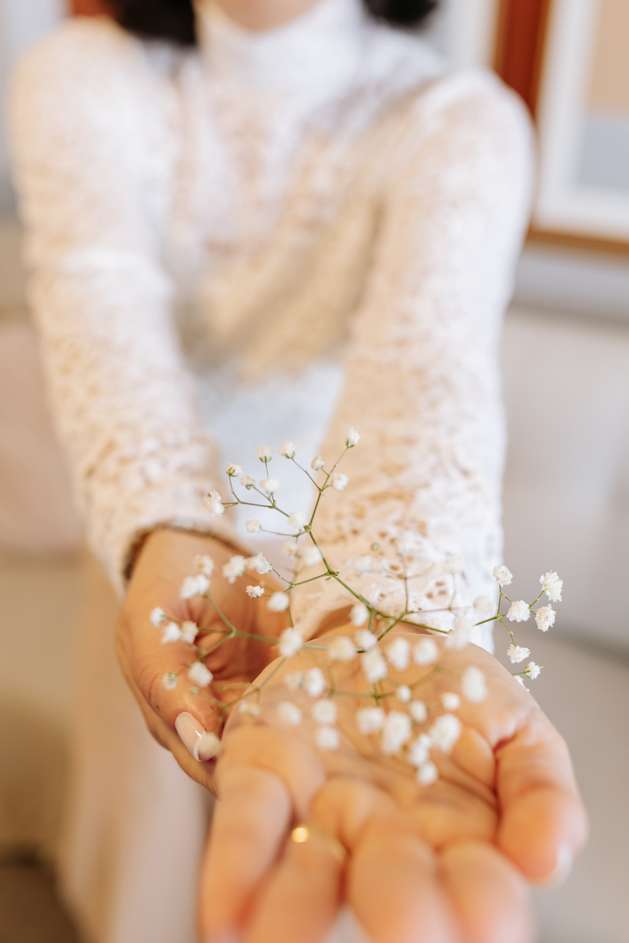 Mãos de Larissa segurando pequenas flores brancas